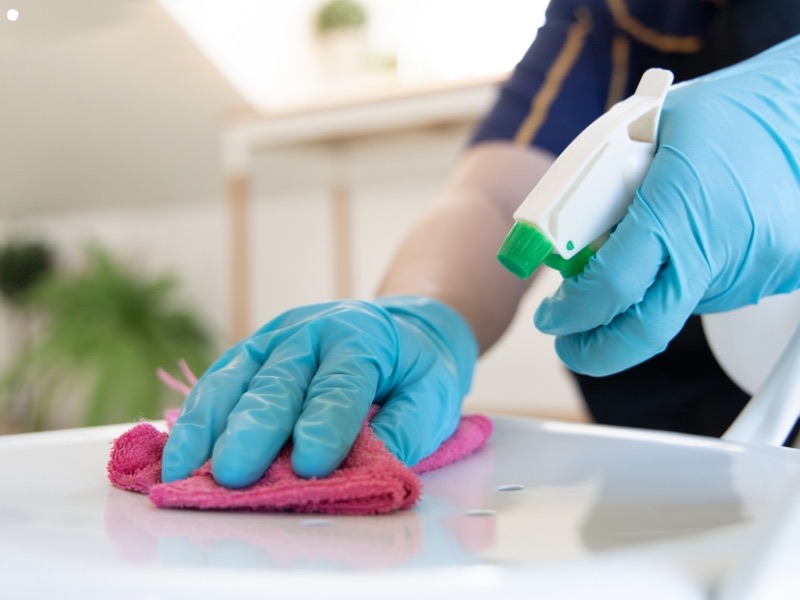 Cleaner deep cleaning a table with spray and microfibre cloth